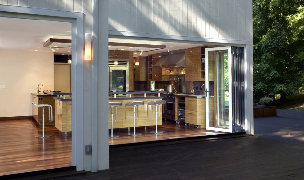 Photo of a modern kitchen in New York with flat-panel cabinets, light wood cabinets and stainless steel appliances.