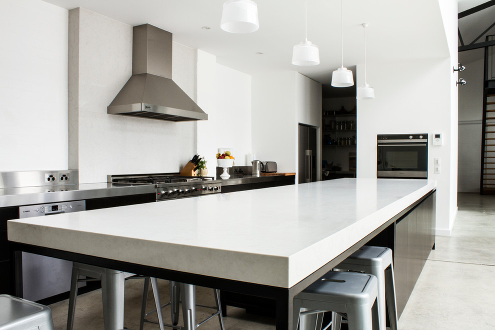 Immagine di un'ampia cucina minimalista con ante in legno bruno, top in quarzo composito, paraspruzzi con piastrelle di metallo, elettrodomestici in acciaio inossidabile e pavimento in cemento