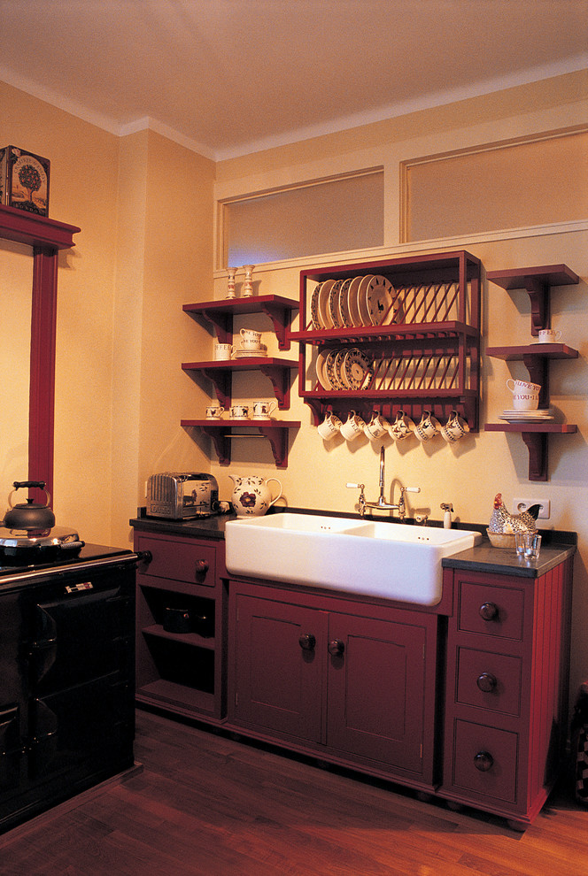 This is an example of a small traditional enclosed kitchen in Amsterdam with a belfast sink, shaker cabinets, red cabinets, marble worktops and medium hardwood flooring.