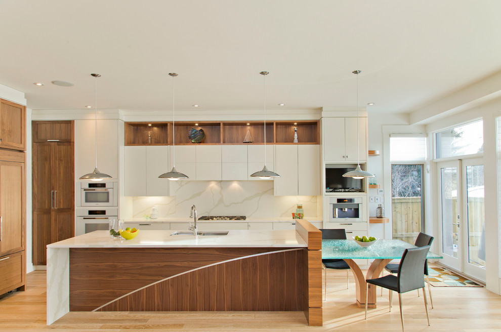 Design ideas for a large contemporary galley open plan kitchen in Calgary with flat-panel cabinets, white cabinets, marble worktops, white splashback, white appliances, light hardwood flooring, an island and marble splashback.