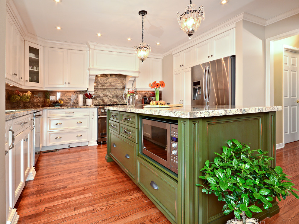 Enclosed kitchen - large traditional u-shaped medium tone wood floor and brown floor enclosed kitchen idea in Toronto with an undermount sink, white cabinets, granite countertops, multicolored backsplash, stone slab backsplash, white appliances, recessed-panel cabinets and an island