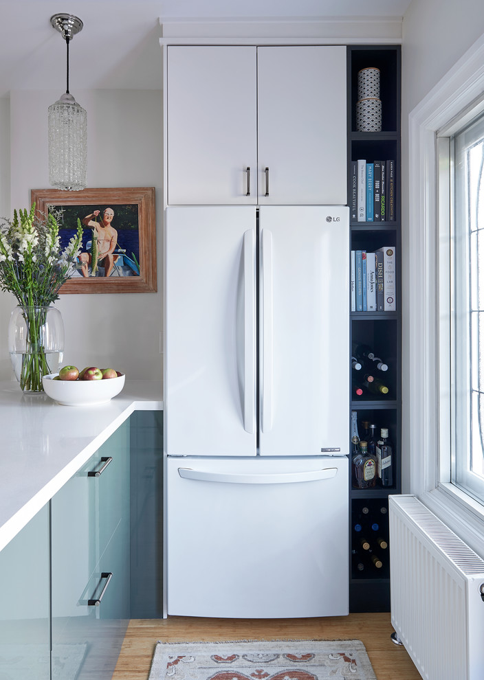 Foto på ett mellanstort skandinaviskt vit l-kök, med en undermonterad diskho, släta luckor, vita skåp, bänkskiva i kvarts, vita vitvaror, bambugolv, en halv köksö och gult golv