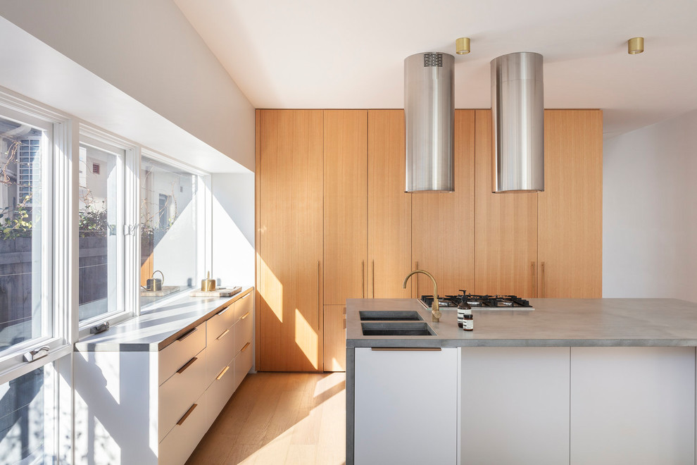 Idee per una cucina minimalista con lavello sottopiano, ante lisce, ante bianche, paraspruzzi a finestra, elettrodomestici da incasso, parquet chiaro, pavimento beige e top grigio