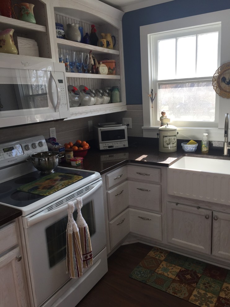 Mid-sized cottage chic u-shaped laminate floor kitchen pantry photo in Other with a farmhouse sink, recessed-panel cabinets, white cabinets, quartzite countertops, gray backsplash, porcelain backsplash, white appliances and a peninsula
