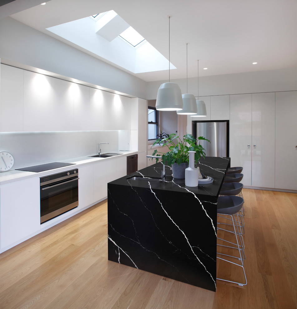 Foto på ett funkis l-kök, med bänkskiva i kvarts, en köksö, en undermonterad diskho, rostfria vitvaror, ljust trägolv och beiget golv