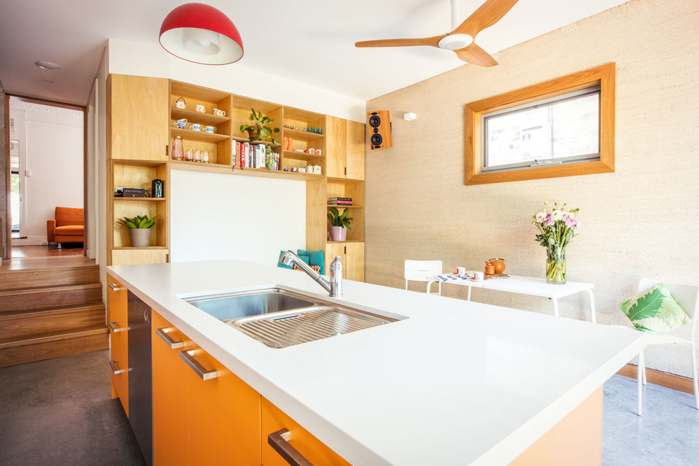 Diseño de cocina bohemia de tamaño medio abierta con fregadero bajoencimera, puertas de armario naranjas, encimera de granito, electrodomésticos blancos, suelo de cemento, una isla y suelo gris