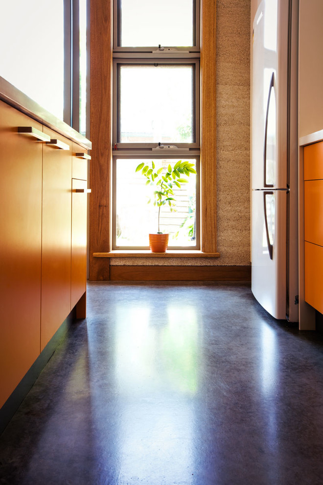 Свежая идея для дизайна: параллельная кухня-гостиная среднего размера в стиле фьюжн с оранжевыми фасадами, гранитной столешницей, белой техникой, бетонным полом, островом и серым полом - отличное фото интерьера