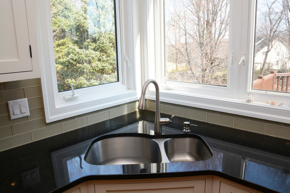 Exemple d'une grande cuisine américaine chic en U avec un évier 2 bacs, un placard à porte shaker, des portes de placard blanches, un plan de travail en granite, une crédence en carreau de verre, un électroménager en acier inoxydable, parquet clair et îlot.