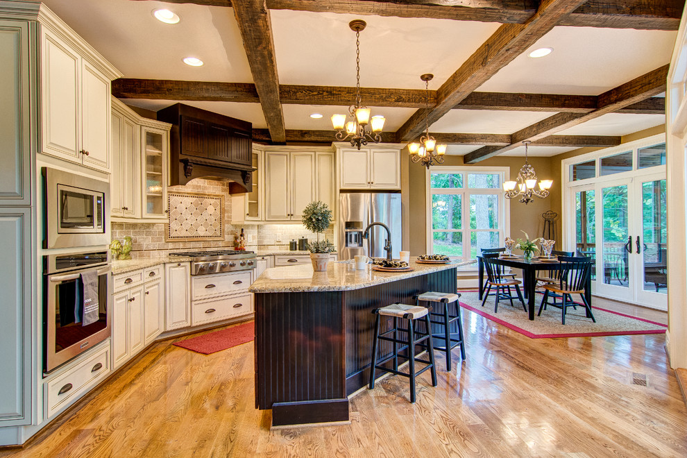 Inspiration for a large timeless l-shaped medium tone wood floor and brown floor eat-in kitchen remodel in Raleigh with an undermount sink, raised-panel cabinets, beige cabinets, granite countertops, beige backsplash, stone tile backsplash, stainless steel appliances and an island