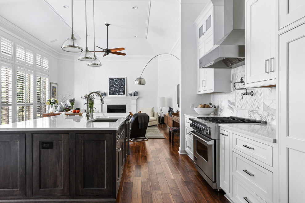 Example of a transitional galley medium tone wood floor and brown floor open concept kitchen design in Jacksonville with an undermount sink, beaded inset cabinets, white cabinets, stainless steel appliances, an island and white countertops
