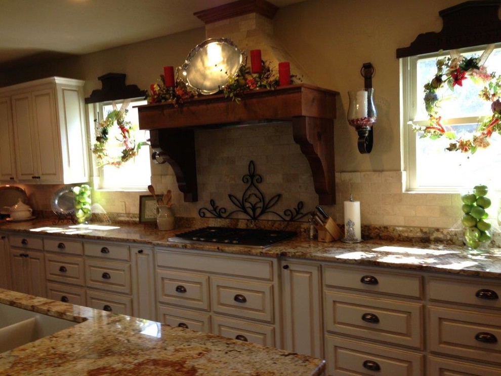 Immagine di una cucina american style con ante con bugna sagomata, ante con finitura invecchiata, top in granito, paraspruzzi beige, paraspruzzi con piastrelle in pietra e elettrodomestici colorati