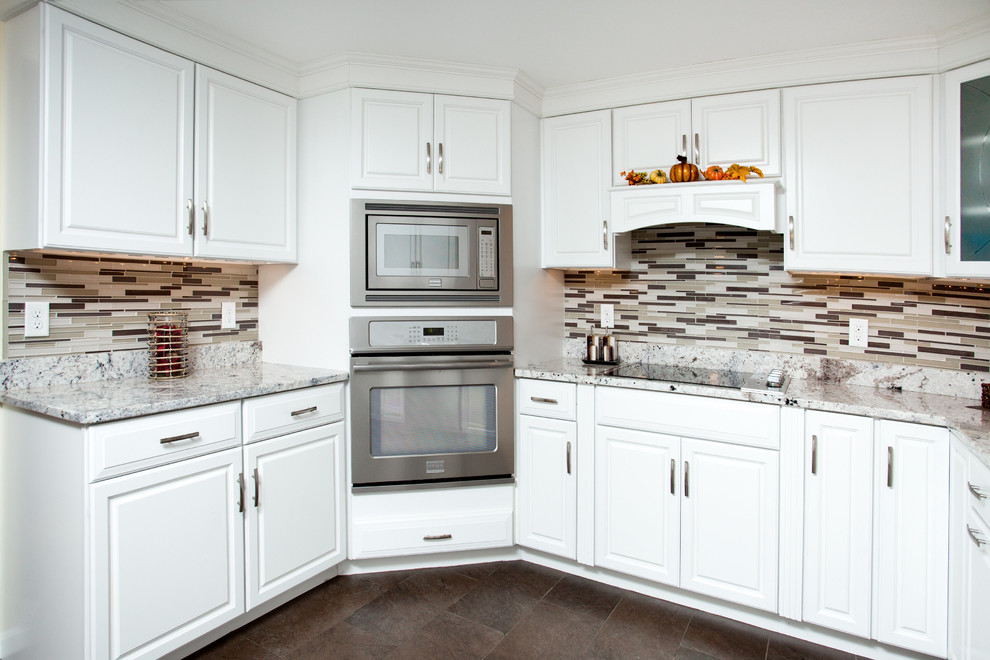 Modern inredning av ett stort kök, med en enkel diskho, luckor med upphöjd panel, vita skåp, granitbänkskiva, flerfärgad stänkskydd, glaspanel som stänkskydd och rostfria vitvaror