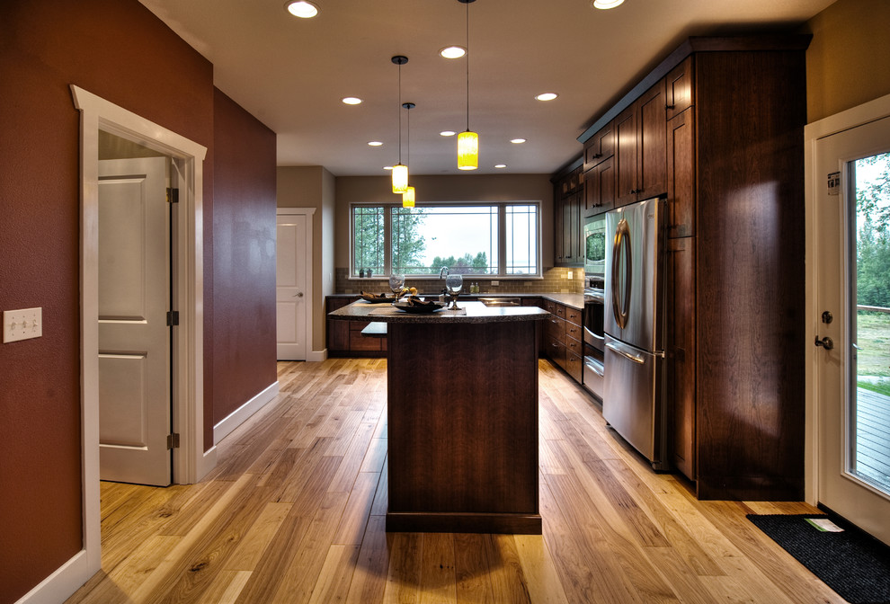 Exempel på ett modernt kök, med en dubbel diskho, luckor med infälld panel, skåp i mörkt trä, granitbänkskiva, beige stänkskydd, stänkskydd i keramik, rostfria vitvaror, ljust trägolv och en köksö