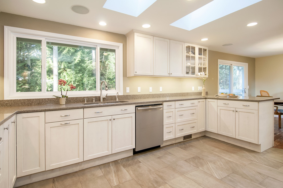 Design ideas for a medium sized classic galley kitchen/diner in Seattle with a submerged sink, shaker cabinets, white cabinets, engineered stone countertops, beige splashback, glass tiled splashback, stainless steel appliances, porcelain flooring and a breakfast bar.