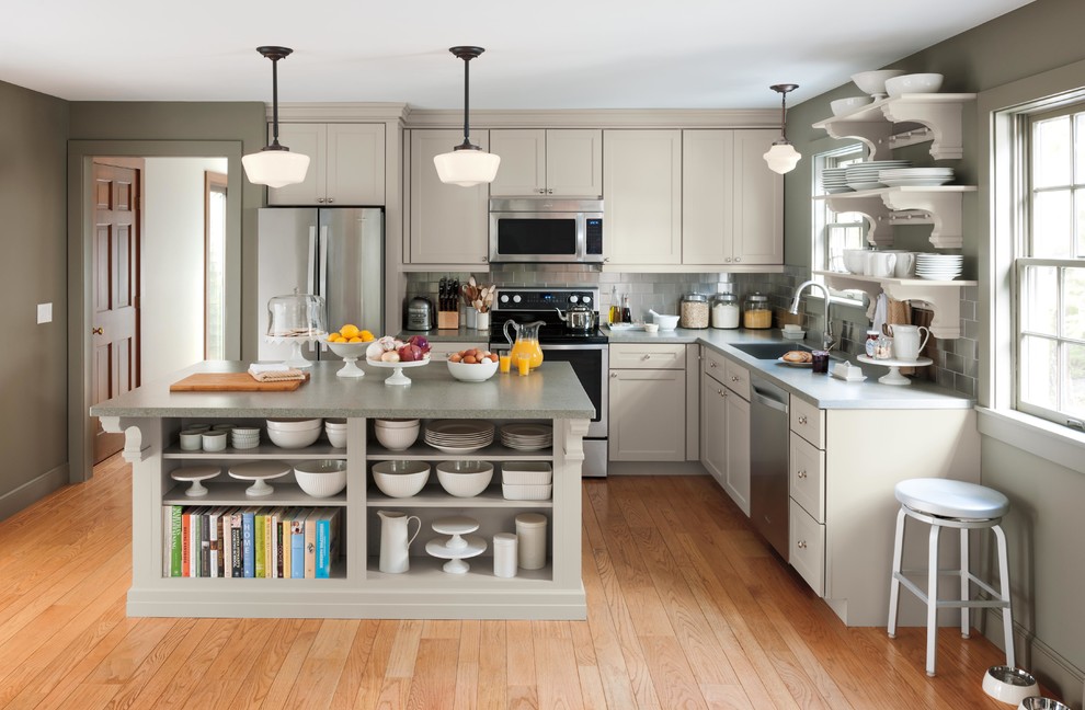 Example of a mid-sized farmhouse l-shaped medium tone wood floor eat-in kitchen design in New York with shaker cabinets, gray cabinets, solid surface countertops, metallic backsplash, stainless steel appliances and an island