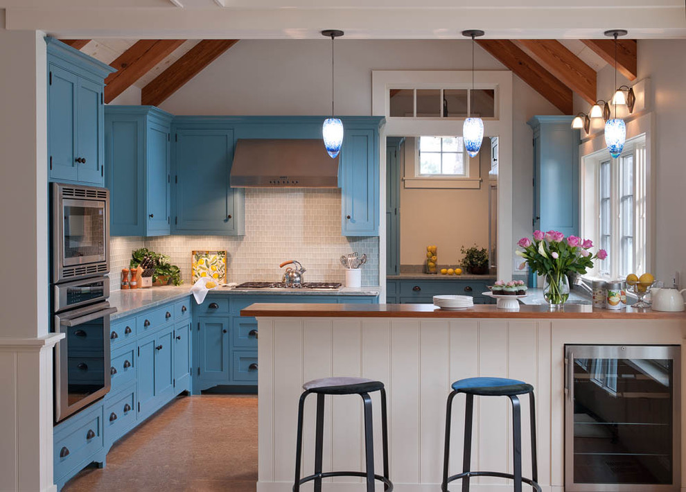 Example of a beach style cork floor kitchen design in Boston with shaker cabinets, blue cabinets, white backsplash, marble countertops, glass tile backsplash, an undermount sink and stainless steel appliances