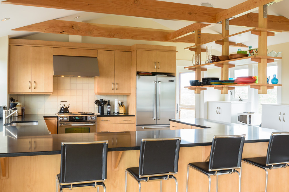 Bild på ett funkis kök, med en undermonterad diskho, släta luckor, skåp i ljust trä, granitbänkskiva, vitt stänkskydd, stänkskydd i keramik och rostfria vitvaror