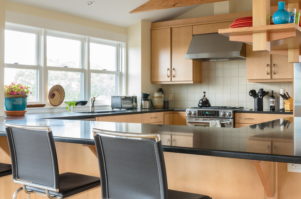 Example of a trendy u-shaped eat-in kitchen design in Boston with an undermount sink, flat-panel cabinets, light wood cabinets, granite countertops, white backsplash, ceramic backsplash and stainless steel appliances