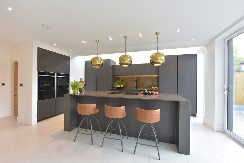 This is an example of a medium sized contemporary open plan kitchen in Manchester with a submerged sink, flat-panel cabinets, grey cabinets, quartz worktops, metallic splashback, glass sheet splashback, black appliances, porcelain flooring, an island, white floors and grey worktops.