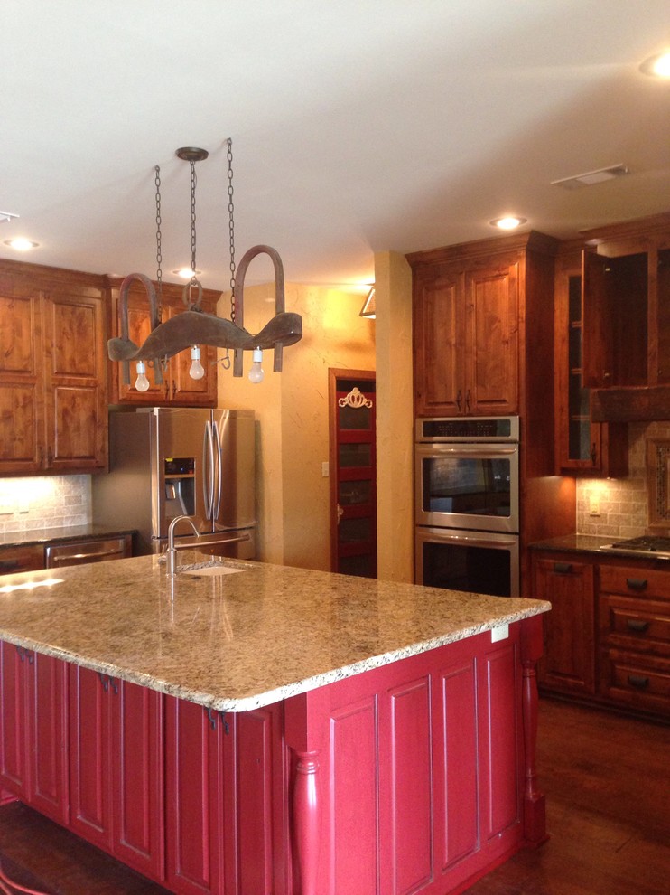 Bild på ett lantligt kök och matrum, med en undermonterad diskho, luckor med upphöjd panel, skåp i mellenmörkt trä, granitbänkskiva, beige stänkskydd, stänkskydd i stenkakel, rostfria vitvaror, mellanmörkt trägolv och en köksö