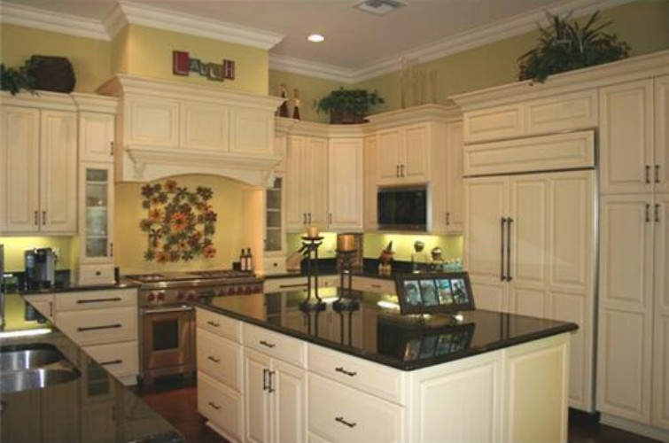Inredning av ett medelhavsstil kök, med en dubbel diskho, luckor med infälld panel, vita skåp, rostfria vitvaror, svart stänkskydd och marmorbänkskiva