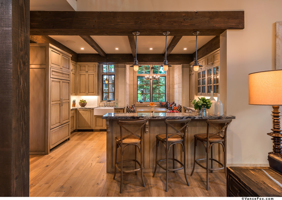 Inspiration for a medium sized rustic l-shaped kitchen/diner in Sacramento with a belfast sink, raised-panel cabinets, light wood cabinets, granite worktops, white splashback, stone tiled splashback, stainless steel appliances, light hardwood flooring and a breakfast bar.