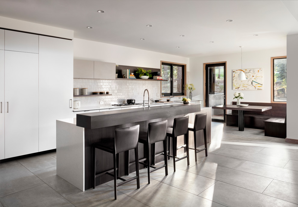 Exempel på ett modernt kök, med släta luckor, vita skåp, vitt stänkskydd, en köksö och grått golv