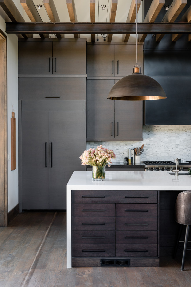 Bild på ett stort funkis vit vitt kök, med en enkel diskho, släta luckor, grått stänkskydd, stänkskydd i stickkakel, integrerade vitvaror, mellanmörkt trägolv, en köksö, brunt golv och skåp i mörkt trä