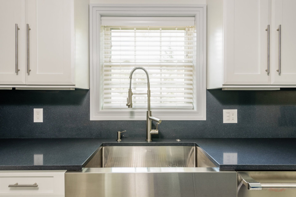 Modern inredning av ett stort blå blått kök, med en rustik diskho, luckor med infälld panel, vita skåp, bänkskiva i kvarts, svart stänkskydd, rostfria vitvaror, marmorgolv, en köksö och flerfärgat golv