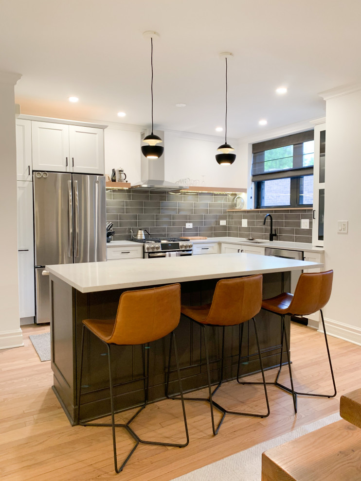 Example of a small transitional l-shaped light wood floor and brown floor eat-in kitchen design in Chicago with an undermount sink, shaker cabinets, white cabinets, quartz countertops, green backsplash, glass tile backsplash, stainless steel appliances, an island and white countertops