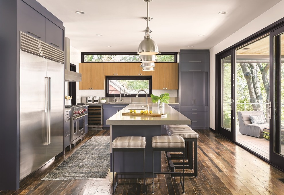 Inspiration for a contemporary l-shaped kitchen in Nashville with a submerged sink, flat-panel cabinets, grey cabinets, white splashback, stainless steel appliances, medium hardwood flooring, an island, brown floors and beige worktops.