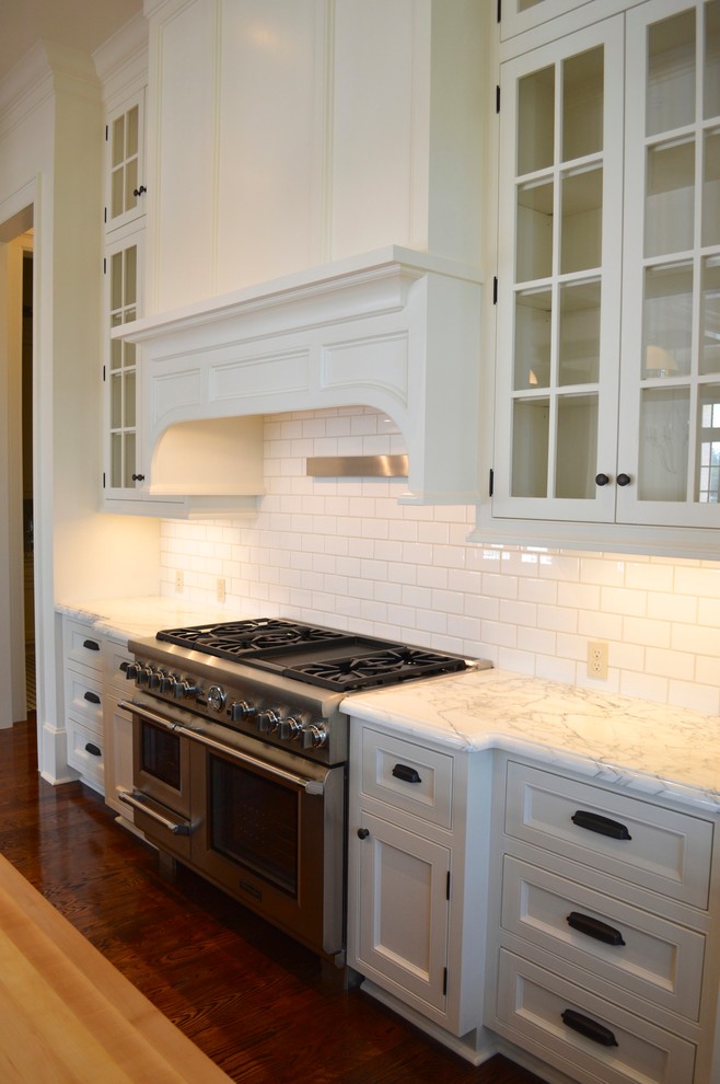 Example of a large transitional u-shaped medium tone wood floor eat-in kitchen design in Houston with flat-panel cabinets, black cabinets, marble countertops, white backsplash and stainless steel appliances