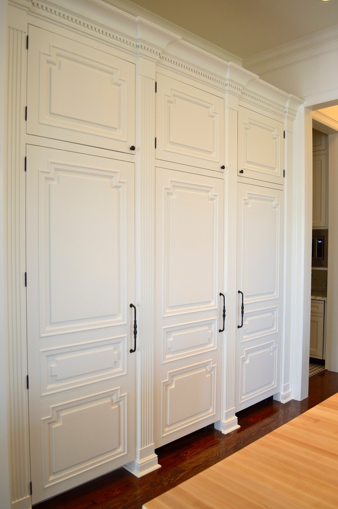 Aménagement d'une grande cuisine américaine encastrable classique en U avec un placard à porte plane, des portes de placard blanches, une crédence blanche et parquet foncé.