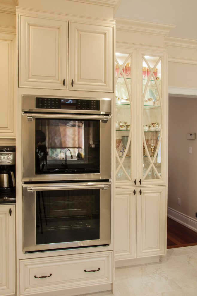 Ejemplo de cocina clásica de tamaño medio con armarios con paneles con relieve, puertas de armario beige, encimera de granito y una isla