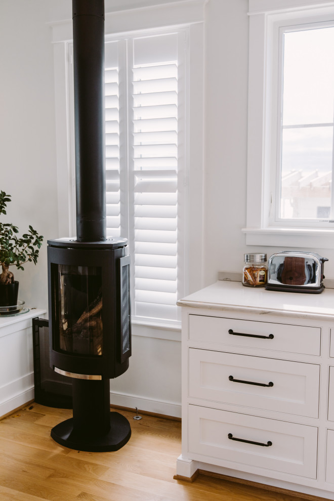 Bild på ett litet funkis grå grått kök, med en rustik diskho, luckor med profilerade fronter, svarta skåp, marmorbänkskiva, grått stänkskydd, stänkskydd i sten, rostfria vitvaror, mellanmörkt trägolv, en köksö och brunt golv