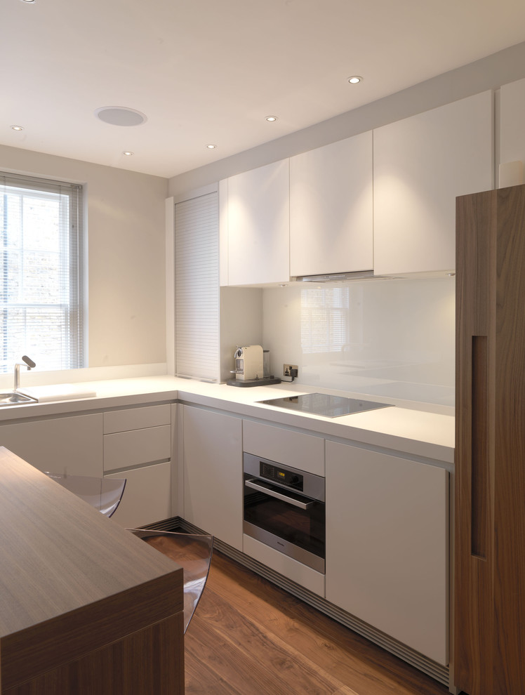 Contemporary u-shaped kitchen in Hampshire with flat-panel cabinets and white cabinets.