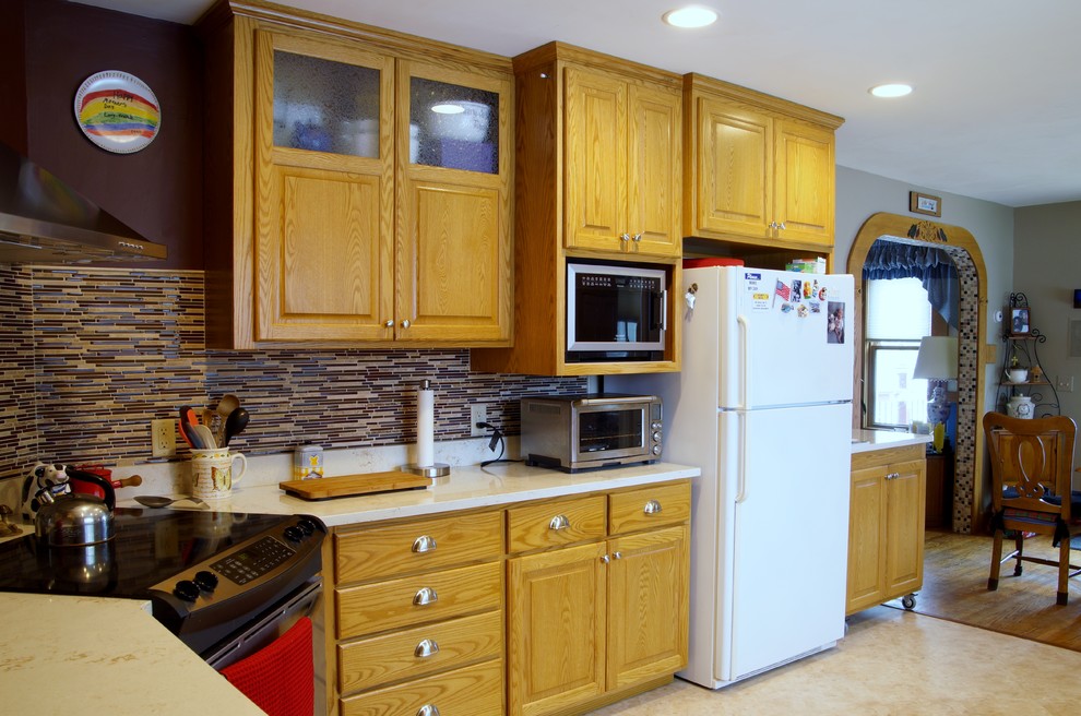 ミネアポリスにある広いコンテンポラリースタイルのおしゃれなキッチン (インセット扉のキャビネット、茶色いキャビネット、クオーツストーンカウンター、茶色いキッチンパネル、ガラス板のキッチンパネル、シルバーの調理設備、クッションフロア、ベージュの床) の写真