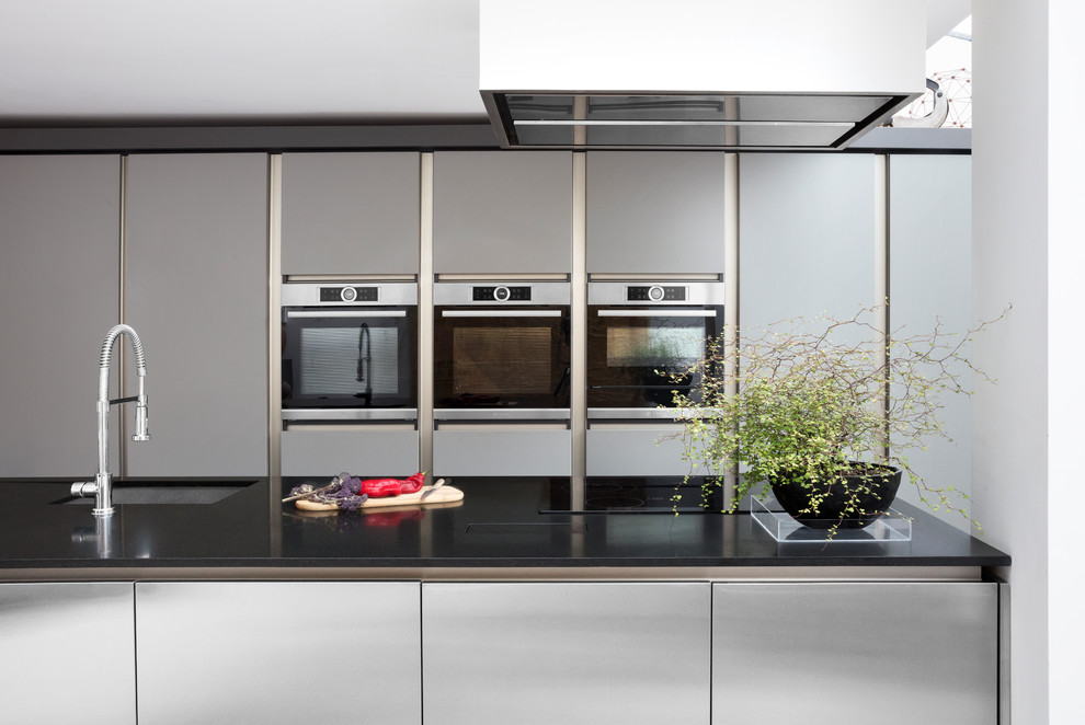 Large contemporary single-wall kitchen/diner in London with recessed-panel cabinets, stainless steel cabinets and an island.