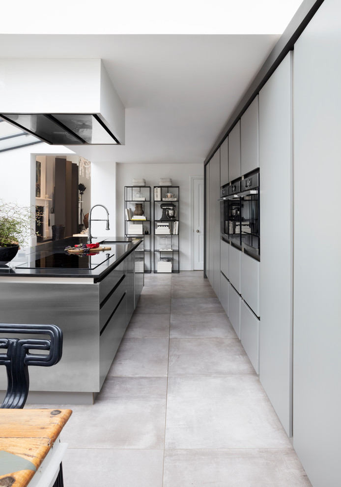 Eat-in kitchen - large contemporary single-wall eat-in kitchen idea in London with recessed-panel cabinets, stainless steel cabinets and an island
