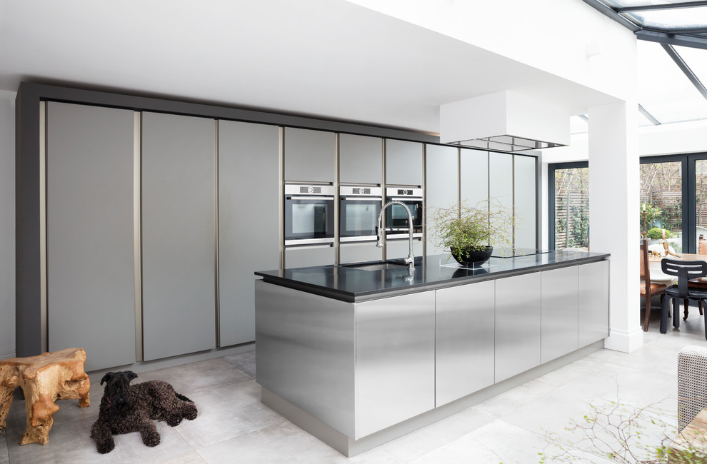 Large contemporary single-wall kitchen/diner in London with recessed-panel cabinets, stainless steel cabinets and an island.
