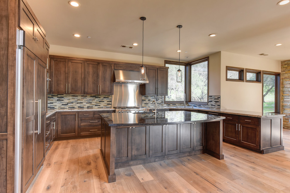 Minimalist u-shaped medium tone wood floor open concept kitchen photo in Sacramento with a drop-in sink, recessed-panel cabinets, dark wood cabinets, granite countertops, multicolored backsplash, mosaic tile backsplash, stainless steel appliances and an island