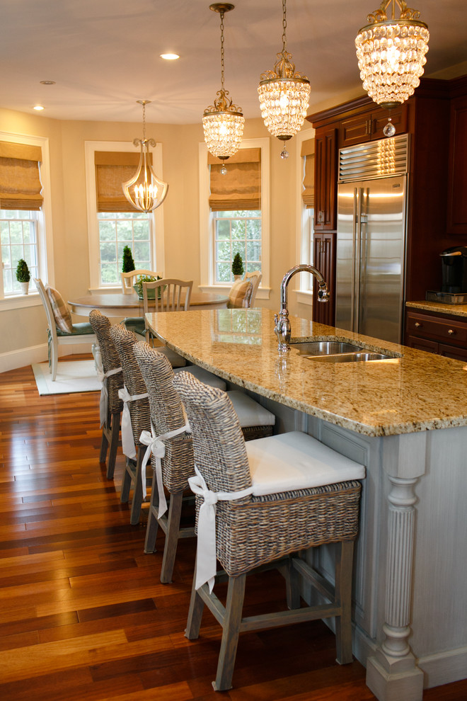 Exempel på ett klassiskt kök och matrum, med en undermonterad diskho, luckor med upphöjd panel, skåp i mörkt trä, rostfria vitvaror, mellanmörkt trägolv och en köksö