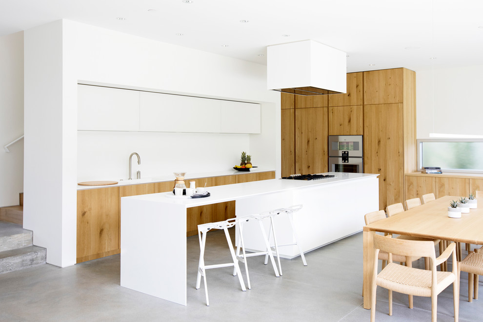 Aménagement d'une cuisine ouverte moderne en bois brun et L avec îlot, un sol gris, un placard à porte plane et sol en béton ciré.