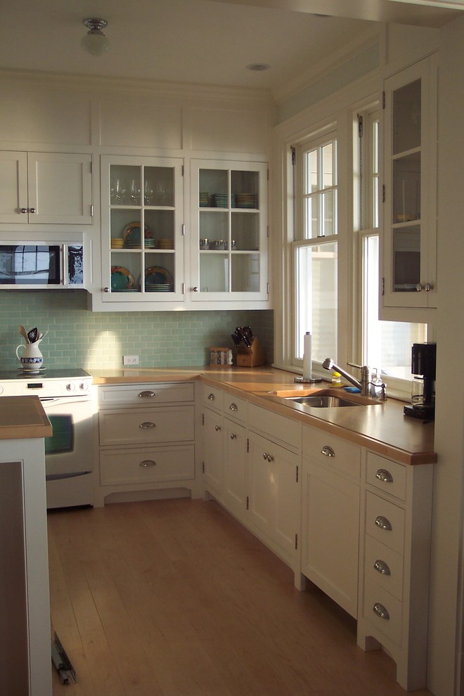 Photo of a beach style l-shaped kitchen/diner in Boston with beaded cabinets, white cabinets, wood worktops, metro tiled splashback, stainless steel appliances and a submerged sink.