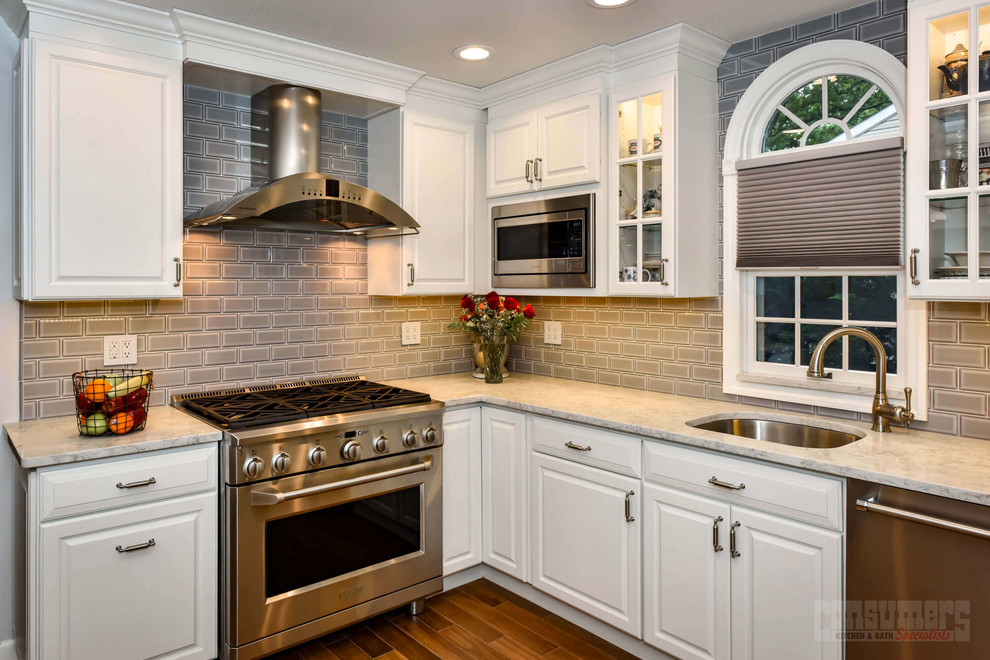 Inspiration for a mid-sized l-shaped eat-in kitchen remodel in New York with an undermount sink, raised-panel cabinets, white cabinets, quartz countertops, gray backsplash, stainless steel appliances and no island