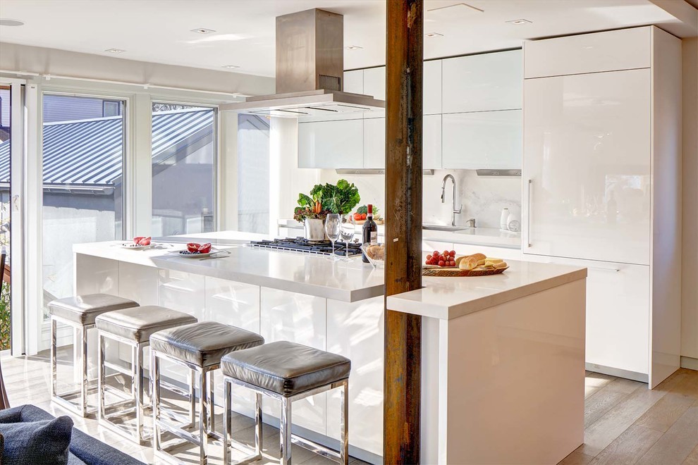 This is an example of a large contemporary galley open plan kitchen in New York with a submerged sink, flat-panel cabinets, yellow cabinets, glass worktops, white splashback, stone slab splashback, integrated appliances, light hardwood flooring, an island and white floors.