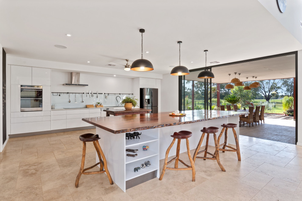 Moderne Küche mit flächenbündigen Schrankfronten, weißen Schränken, Küchenrückwand in Weiß, Glasrückwand, Küchengeräten aus Edelstahl, beigem Boden, weißer Arbeitsplatte und zwei Kücheninseln in Perth