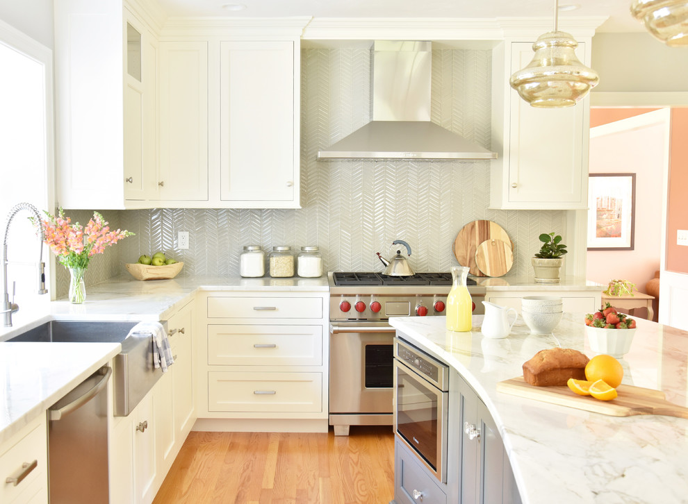 Klassische Küche mit Landhausspüle, Schrankfronten mit vertiefter Füllung, Quarzit-Arbeitsplatte, Küchenrückwand in Grau, Rückwand aus Glasfliesen, Küchengeräten aus Edelstahl, hellem Holzboden, Kücheninsel und weißer Arbeitsplatte in Boston