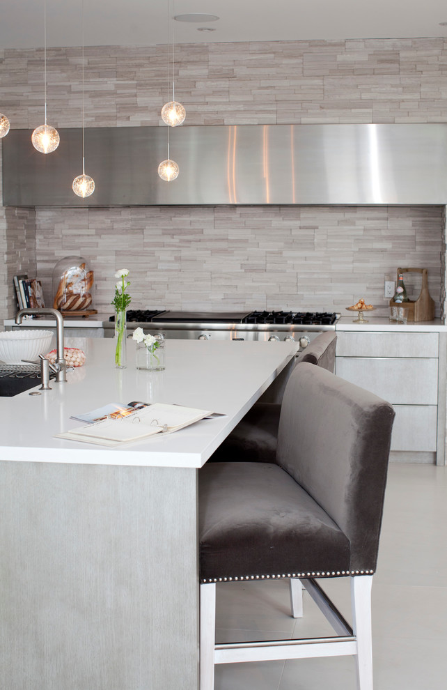Foto di una cucina minimal con ante lisce, ante grigie, paraspruzzi grigio, paraspruzzi con piastrelle in pietra e elettrodomestici in acciaio inossidabile