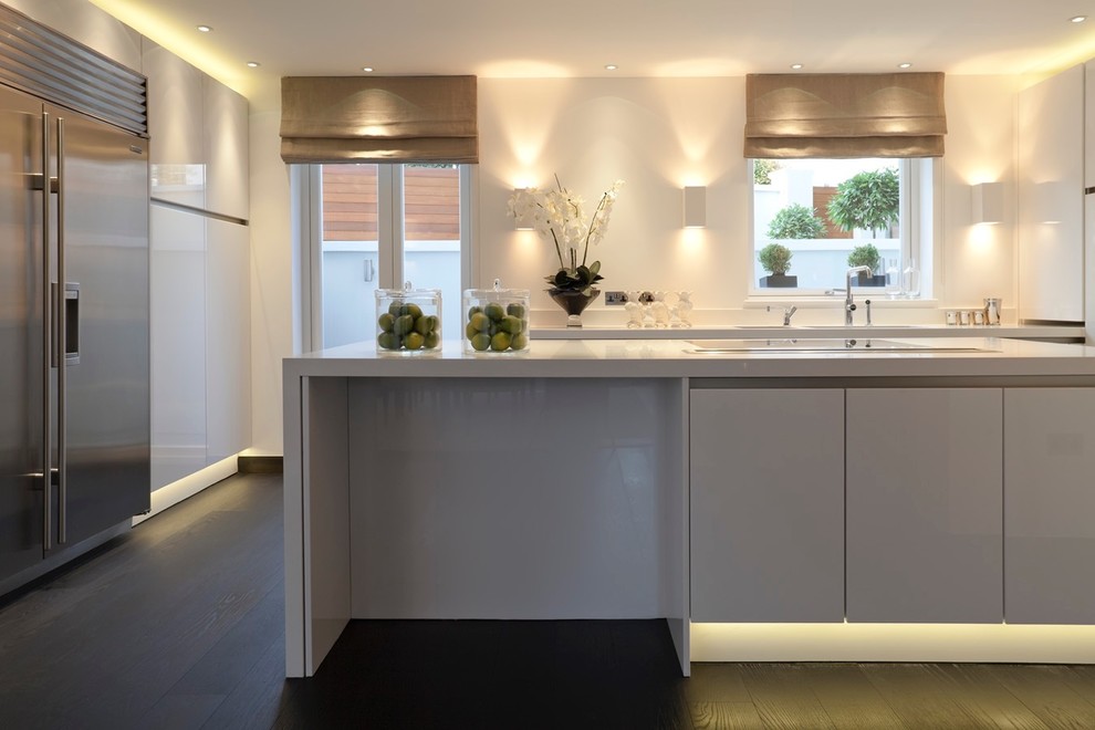 Geschlossene, Mittelgroße Moderne Küche mit Doppelwaschbecken, flächenbündigen Schrankfronten, weißen Schränken, dunklem Holzboden, Kücheninsel und schwarzem Boden in London